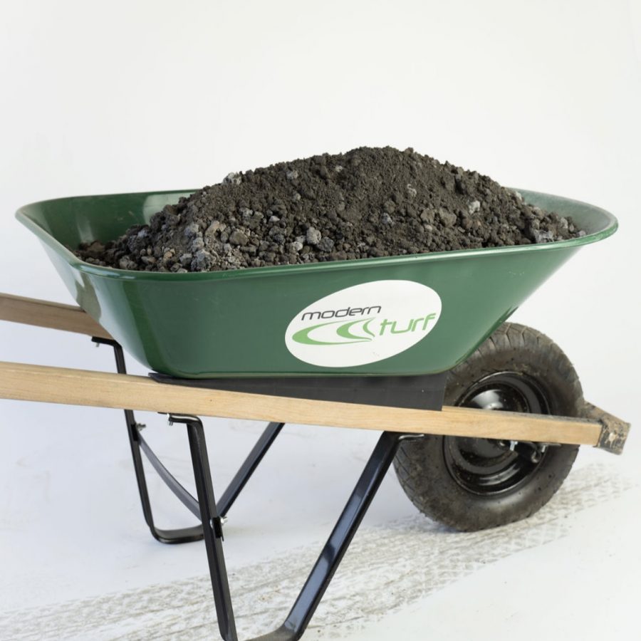 A green wheelbarrow filled with soil, labeled modern turf, on a white background.