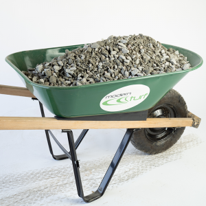 Green wheelbarrow filled with gravel, labeled modern turf, on a white background.